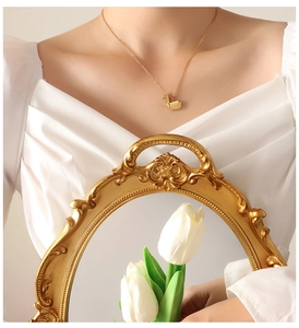 Detail van een gouden origami kraanvogel hanger ketting gedragen op een witte top top