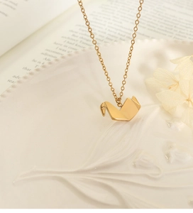 Gouden origami kraanvogel ketting gepresenteerd op een wit keramisch bord