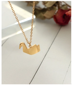 Gedetailleerde close-up van een gouden origami kraanvogel hanger met metallic glans