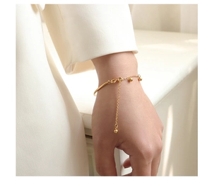 Detail of 18k gold plated bangle with integrated ball chain and adjustable closure