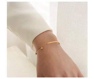Detail of 18k gold plated titanium steel bracelet with beads and half-solid tube design