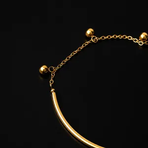 Close-up of gold plated steel bracelet with sleek arc bar, fine chain and metal beads