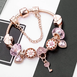Pulsera de dijes en oro rosa con colgantes de corazón rosa y llave en cadena de serpiente