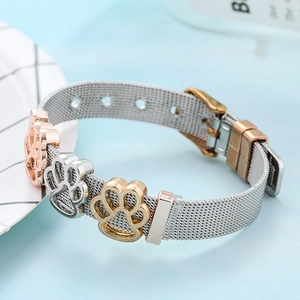 Stainless steel mesh bracelet with golden and silver paw charms on light blue background