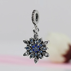 Macro shot of silver snowflake charm with gradient blue crystals and textured loop detail