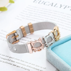 Pulsera de malla de acero con dijes de gato en oro rosa y plata sobre tarjeta