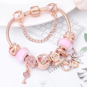 Detalle de pulsera de oro rosa con cristales rosas, noria y colgante de llave