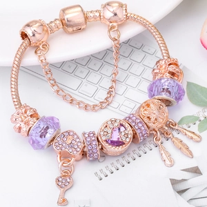 Pulsera de oro rosa con cuentas de cristales púrpuras, llaves y dijes de plumas