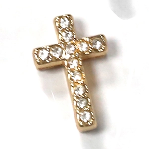 Macro shot of gold-plated cross charm with sparkling rhinestones and beaded edges