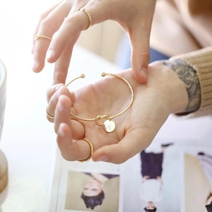 Detailed view of a gold knot cuff bracelet featuring a personalized letter K charm