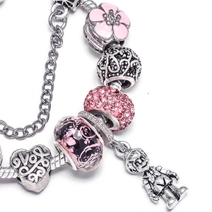 Rosa Charm-Armband mit Emaille-Blumen, Herzanhänger und Kristallen auf weißem Grund