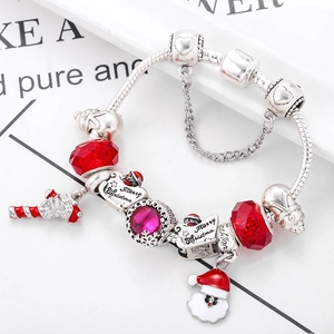 Macro shot of silver snake chain bracelet with red crystal beads and Santa Claus charms