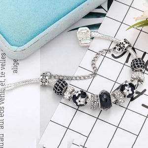 Elegant charm bracelet with black enamel flowers and sparkling crystals on snake chain