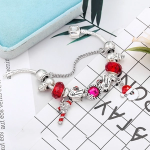 Close-up of DIY Christmas charm bracelet with red beads and Santa Claus pendants