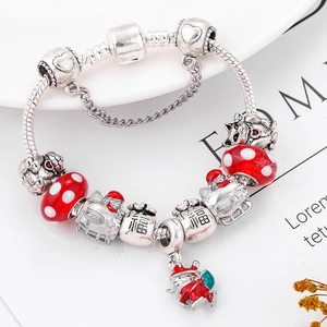 Macro detail of silver snake chain bracelet with red crystal beads and Santa pendant