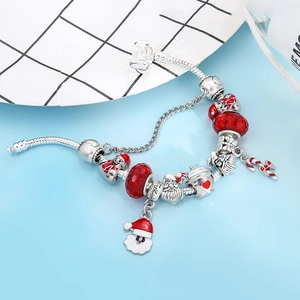 Macro detail of Christmas DIY charm bracelet with Santa Claus and festive red beads