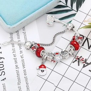 Detail of Christmas charm bracelet with red beads and holiday pendants on a blue box