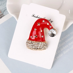 Vue macro de broche chapeau de Noël en émail rouge avec étoiles dorées et cristaux blancs