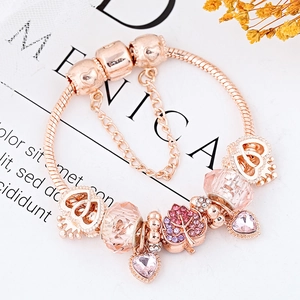 Bracelet serpent or rose avec perles en cristal rose et breloques cœur sur fond magazine