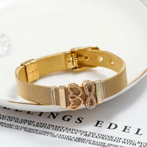 Golden mesh bracelet with sparkling infinity and intertwined hearts charms on a white plate