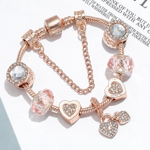 Rose gold snake chain bracelet with heart charms and pink crystals on white background