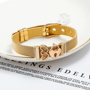Golden mesh bracelet featuring hollow heart and padlock charms on a white ceramic plate