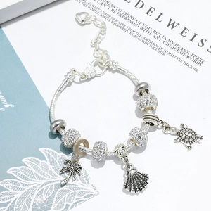 Macro detail of silver bead bracelet featuring coconut tree, sea snail, and turtle charms