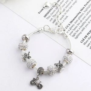 Detailed close-up of a silver charm bracelet with windmill and bicycle pendants