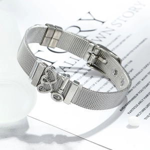 Detail of 10mm silver mesh strap bracelet featuring interlocking heart charms on a magazine