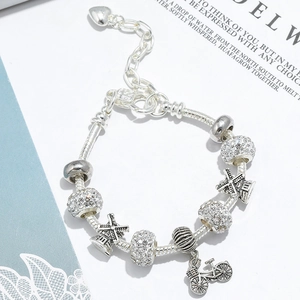 Detailed shot of silver heart charm bracelet with bicycle and windmill pendants