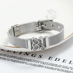 Detail of silver mesh watch band bracelet featuring hollow heart and key charms
