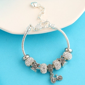 Detail of silver snake chain bracelet with windmill charms and vintage bicycle pendant