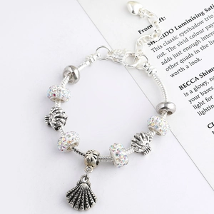 Detail of silver-plated bracelet featuring ocean charms and a large shell pendant on snake chain