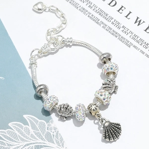 Macro shot of silver seashell charms and sparkling rhinestones on the snake chain bracelet