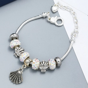 Detailed view of silver charm bracelet with shell pendant and sparkling rhinestones