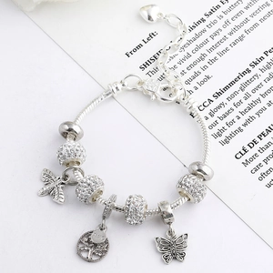 Close-up of silver-plated heart bracelet featuring bee, tree of life, and butterfly charms