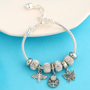Macro shot of silver snake chain bracelet featuring family tree and bee pendants