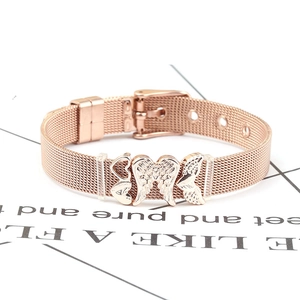 Detail of rose gold mesh bracelet featuring heart and wing charms with pin buckle