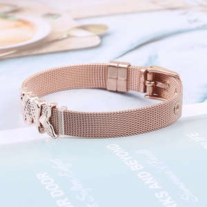 Detailed macro view of rose gold mesh bracelet with adjustable buckle and angel wing charms
