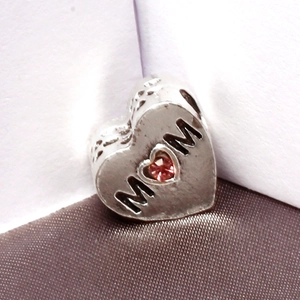 Makro-Detail des silbernen Herzanhängers mit rosa Edelstein und MOM-Gravur für Armbänder