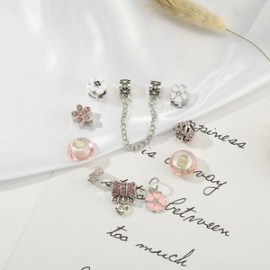 Set de charms DIY rosas con lazo de corazón y cuentas de flores sobre satén blanco