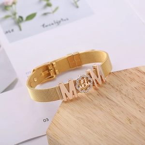 Goldenes Mesh-Armband mit MOM-Schriftzug und Strass auf einem Holzblock