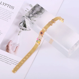 Golden Milanese mesh bracelet with sunflower and heart charms on magazine background