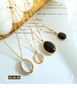 Detail of layered gold beaded necklaces with black and white oval pendants on a vintage tray