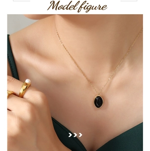 Close-up of elegant gold chain necklace with black oval stone pendant on a female model