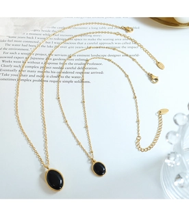 Detail of vintage gold necklace with black cat-eye pendants and K18 metal tag