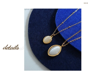 Detail of vintage gold chain necklace featuring dual-sized oval cat-eye stone pendants