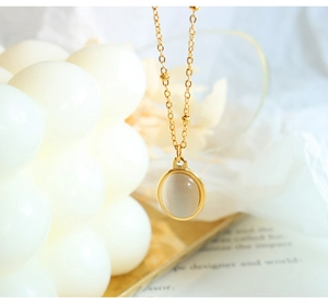 Detailed close-up of a gold cat-eye stone pendant on a delicate beaded chain necklace