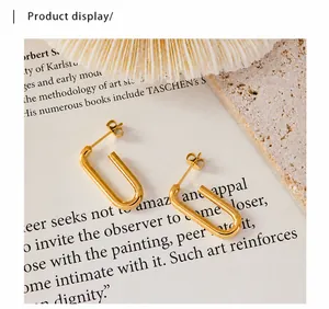 Nahaufnahme goldener geometrischer U-Ohrringe mit poliertem Finish auf einem Kunstbuch