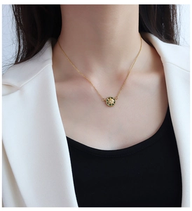 Detail of 18K gold-plated starburst pendant necklace with green enamel on a model